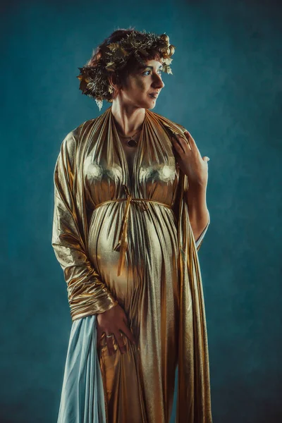 Pregnant woman in golden toga and wreath posing like a Greece fertility goddess — Stock Photo, Image