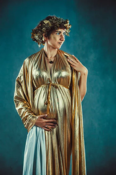 Pregnant woman in golden toga and wreath posing like a Greece fertility goddess — Stock Photo, Image