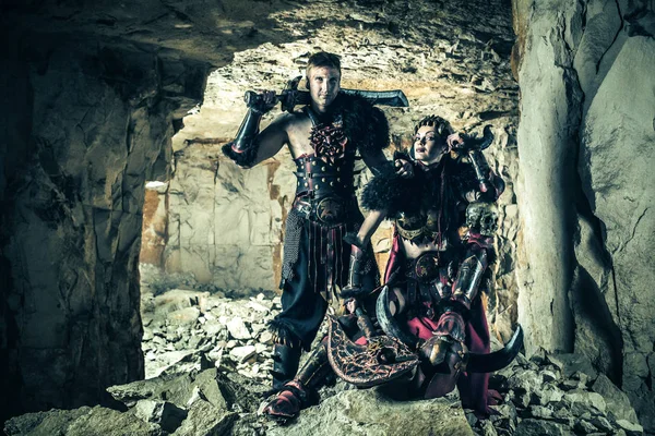 Couple of vikings in armor with swords. Catacombs on the background. — Stock Photo, Image