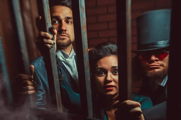 Dois cavalheiros e uma senhora atrás das grades na prisão. . — Fotografia de Stock