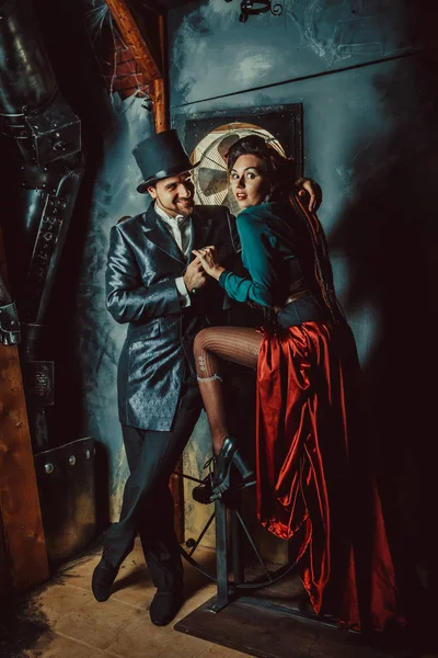 Joli couple flirtant vêtu de costumes vintage sur le fond de la pièce sombre . — Photo