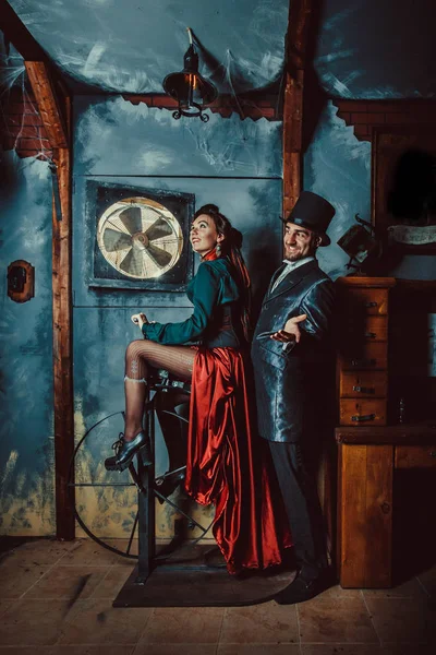Bastante pareja coqueta vestida con trajes vintage en el fondo de la habitación oscura . — Foto de Stock