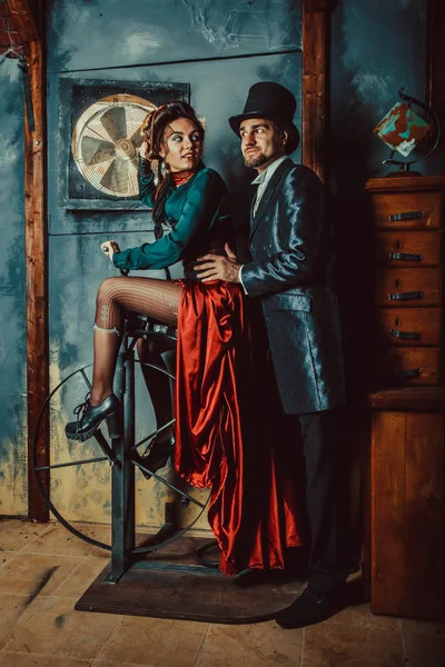 Joli couple flirtant vêtu de costumes vintage sur le fond de la pièce sombre . — Photo