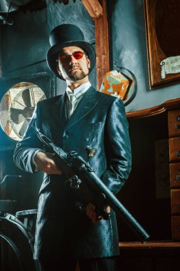 Karanlık bir odada arka plan üzerinde bir tüfekle olgun beyefendi.