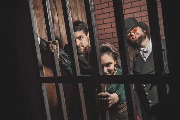 Two gentlemen and a lady behind bars in the prison. — Stock Photo, Image