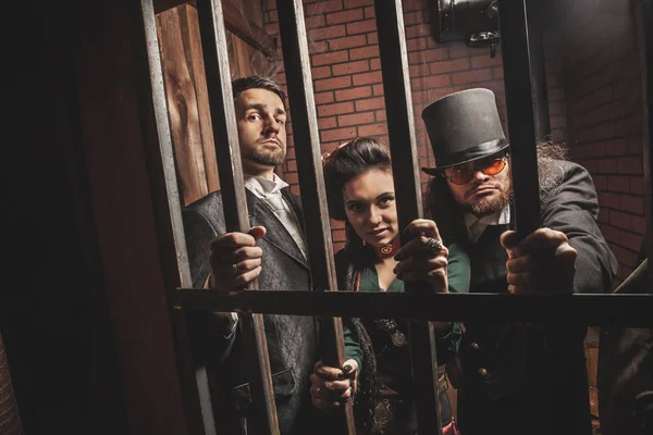 Two gentlemen and a lady behind bars in the prison. — Stock Photo, Image
