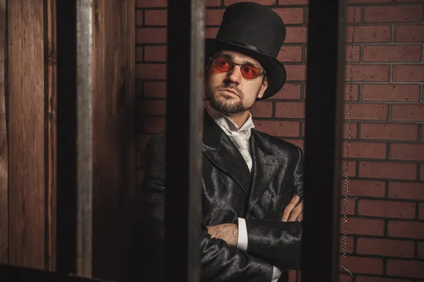 Smart gentleman in cylinder hat and tie in the prison cage. — Stock Photo, Image