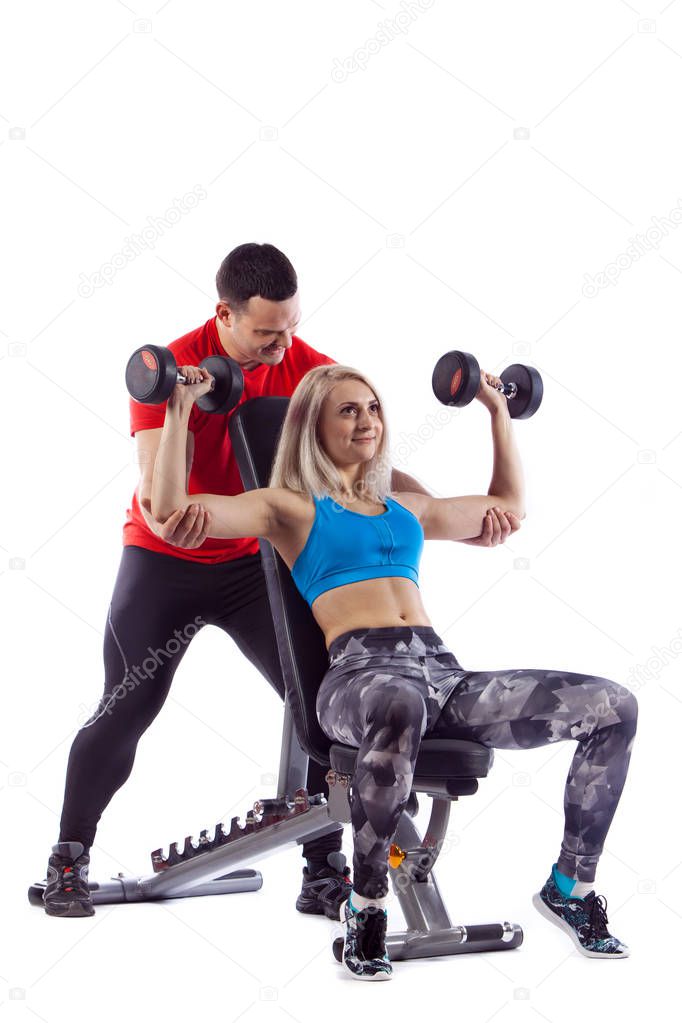 Personal trainer man is teaching woman lifting a dumbbell.