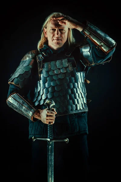 Powerful blond knight with the sword on the dark background — Stock Photo, Image