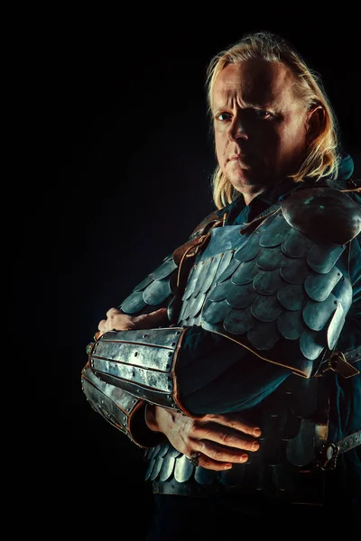 Powerful blond knight is standing with the crossed arms on the dark background — Stock Photo, Image