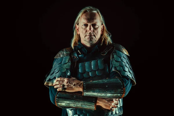 Сильный рыцарь-блондин стоит со скрещенными руками на темном фоне — стоковое фото