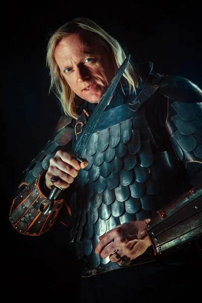 Krachtige blond ridder met het zwaard op de donkere achtergrond — Stockfoto