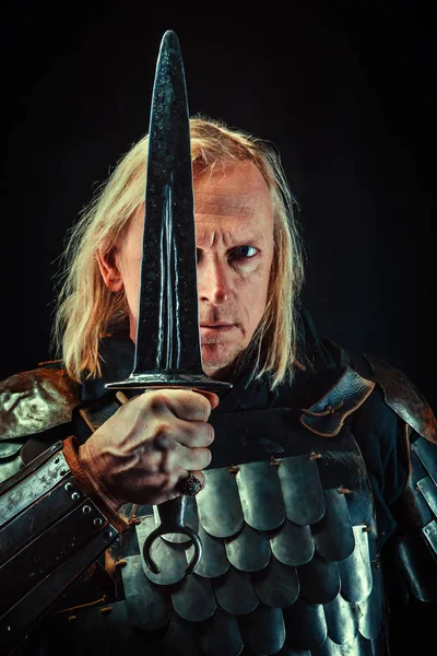 Мощный рыцарь-блондин с мечом на темном фоне — стоковое фото