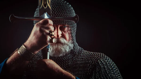 Сильный бородатый рыцарь с мечом на темном фоне — стоковое фото