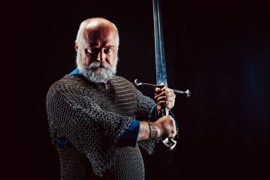 Koyu arka plan üzerinde kılıçla güçlü sakallı knight