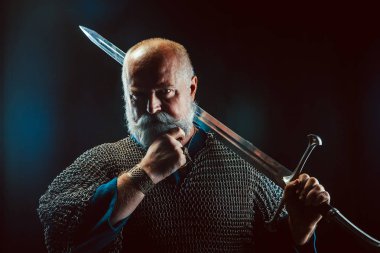 Koyu arka plan üzerinde kılıçla güçlü sakallı knight