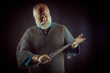 Koyu arka plan üzerinde kılıçla güçlü sakallı knight