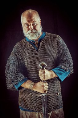 Koyu arka plan üzerinde kılıçla güçlü sakallı knight