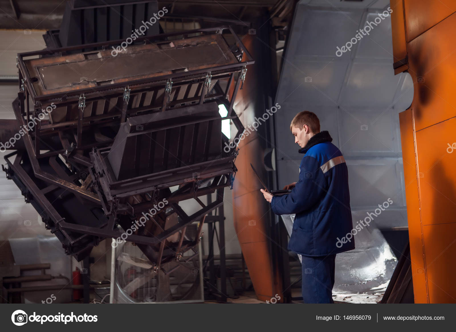 Molding plastics in the huge factory oven. Worker with the laptop is