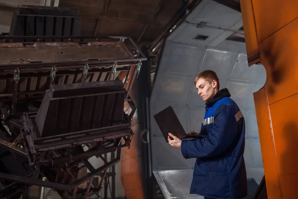 Kunststoffe im riesigen Fabrikbackofen formen. Arbeiter mit dem Laptop steuert den Formprozess. — Stockfoto