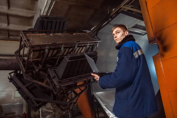 Spuitgieten van kunststoffen in de enorme fabriek oven. Werknemer met de laptop is het regelen van de molding proces. — Stockfoto