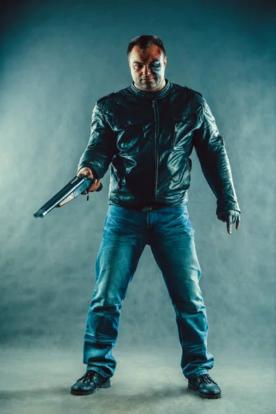 Dangerous man with scares and burns on the face is holding a shotgun. — Stock Photo, Image