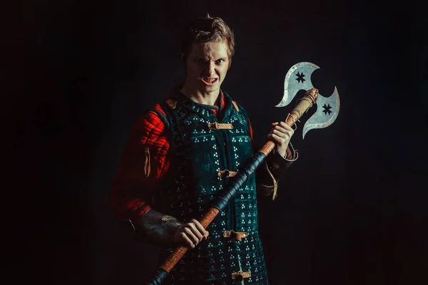 Young medieval warrior with the axe. Dark background. — Stock Photo, Image