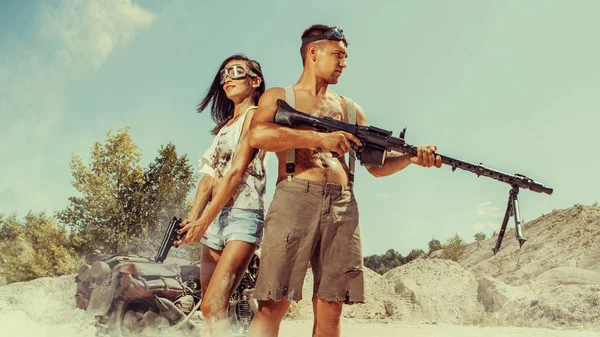Sexy couple of bikers with the guns on the desert background. — Stock Photo, Image