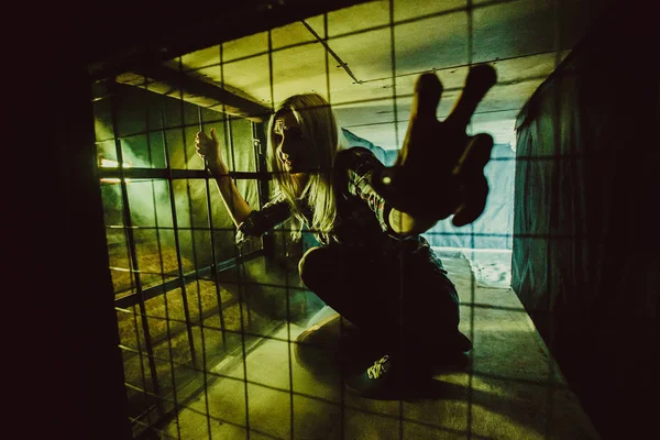 Frightened blond woman in the dark cage. — Stock Photo, Image