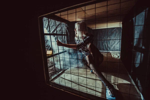Φοβισμένη ξανθιά γυναίκα στο σκοτεινό κλουβί. — Φωτογραφία Αρχείου