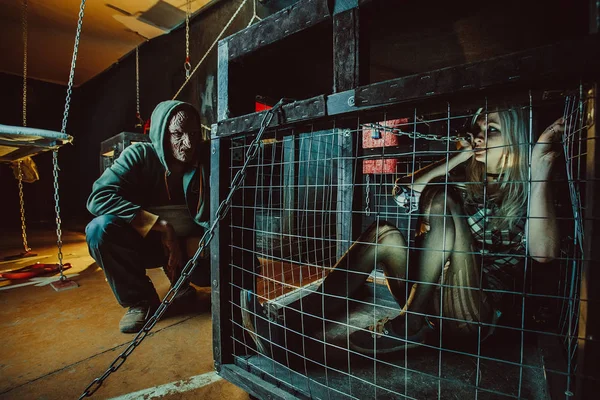 Bloody maniac and his female victim in the cage. — Stock Photo, Image