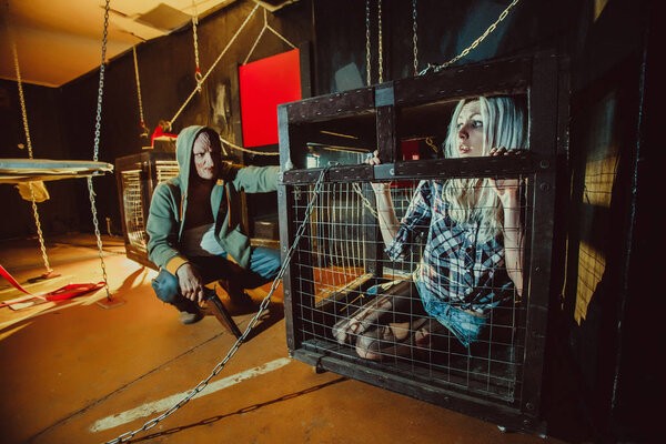 Bloody maniac and his female victim in the cage.