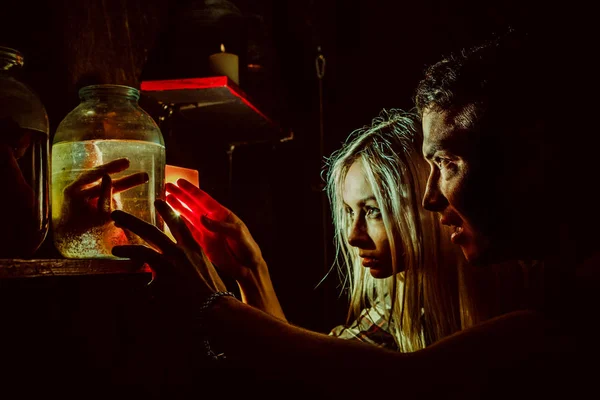 Frightened couple is looking at the canned limbs in the maniac's lair. — Stock Photo, Image