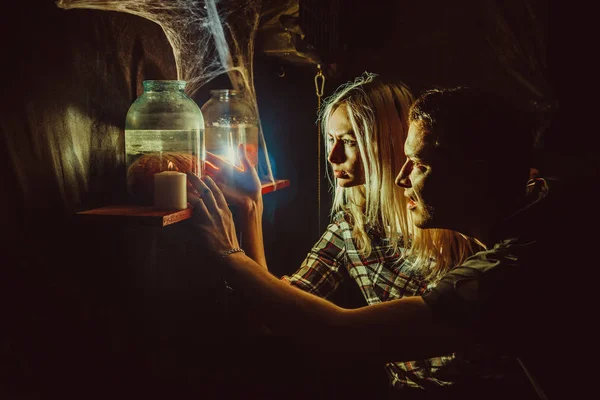 Frightened couple is looking at the canned limbs in the maniac's lair. — Stock Photo, Image