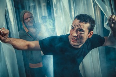 Korkmuş bir adamım labirent bir çıkış bulmaya çalışıyor. Manyak arka planda chainsaw ile.