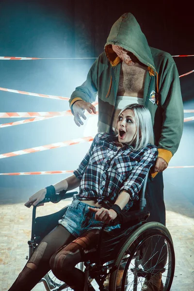 Maniac et sa victime attachée dans le fauteuil roulant sur le fond sombre . — Photo