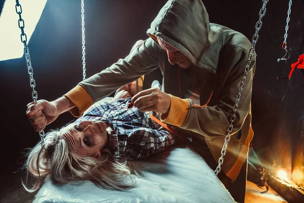 Maniac is feeding his tied victim with the cockroach in the dark room. — Stock Photo, Image