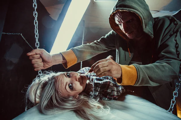 Maniac is feeding his tied victim with the cockroach in the dark room. — Stock Photo, Image