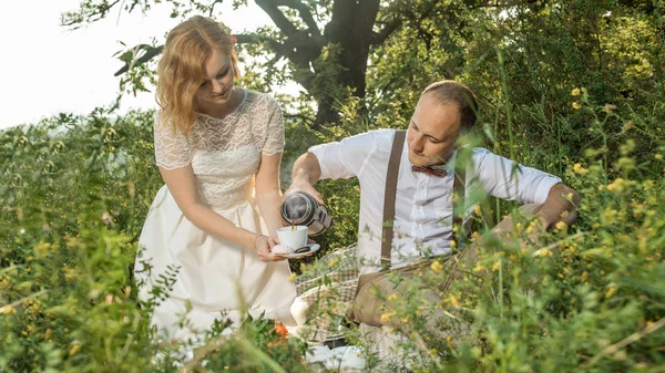 Casal atraente desfrutando de piquenique romântico ao pôr do sol no campo — Fotografia de Stock