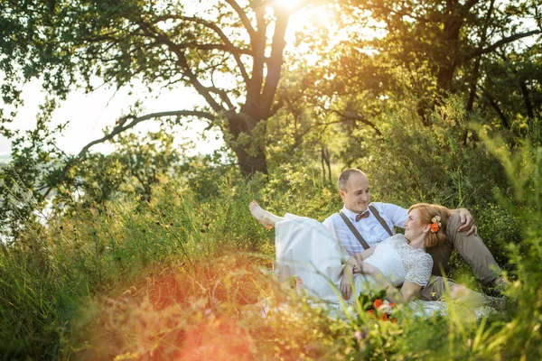 Casal atraente desfrutando de piquenique romântico ao pôr do sol no campo — Fotografia de Stock