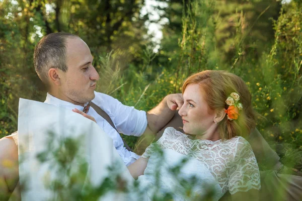 Casal atraente desfrutando de piquenique romântico ao pôr do sol no campo — Fotografia de Stock