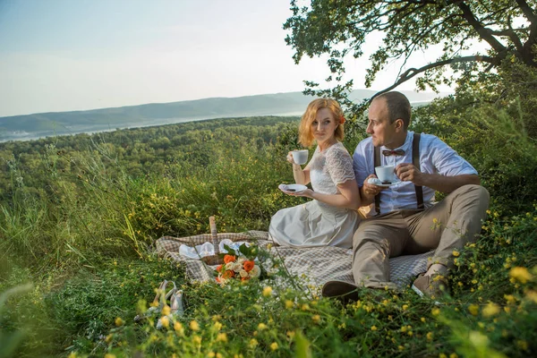 Atractiva pareja disfrutando de un romántico picnic al atardecer en el campo —  Fotos de Stock