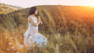 Doğa açık havada üzerinde doğum öncesi yoga yaparken güzel hamile kadın.