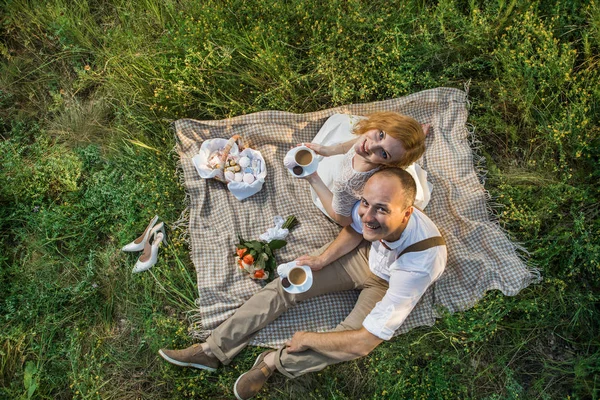 Atractiva pareja disfrutando de un romántico picnic al atardecer en el campo —  Fotos de Stock