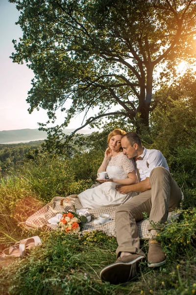 Attraktivt par njuter av romantisk solnedgång picknick på landsbygden — Stockfoto