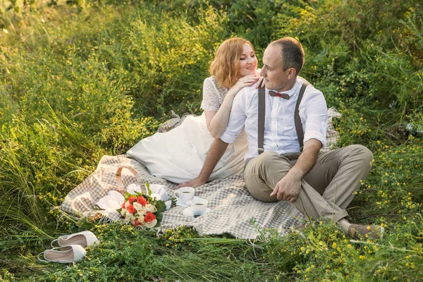 Casal atraente desfrutando de piquenique romântico ao pôr do sol no campo — Fotografia de Stock