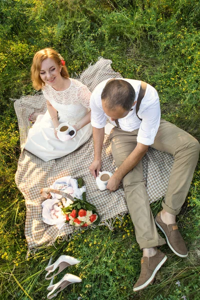 Casal atraente desfrutando de piquenique romântico ao pôr do sol no campo — Fotografia de Stock