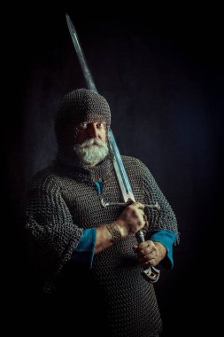 Koyu arka plan üzerinde kılıçla güçlü sakallı knight
