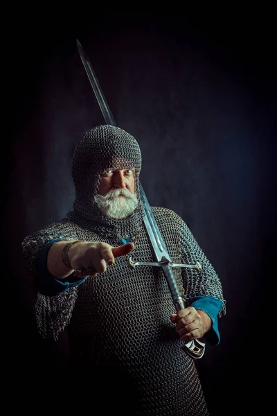 Poderoso cavaleiro barbudo com a espada no fundo escuro — Fotografia de Stock