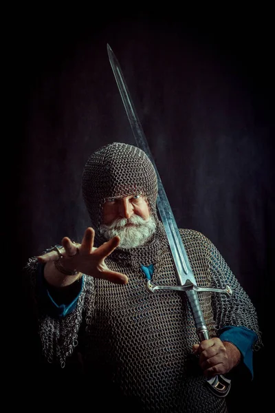 Potente cavaliere barbuto con la spada sullo sfondo scuro — Foto Stock